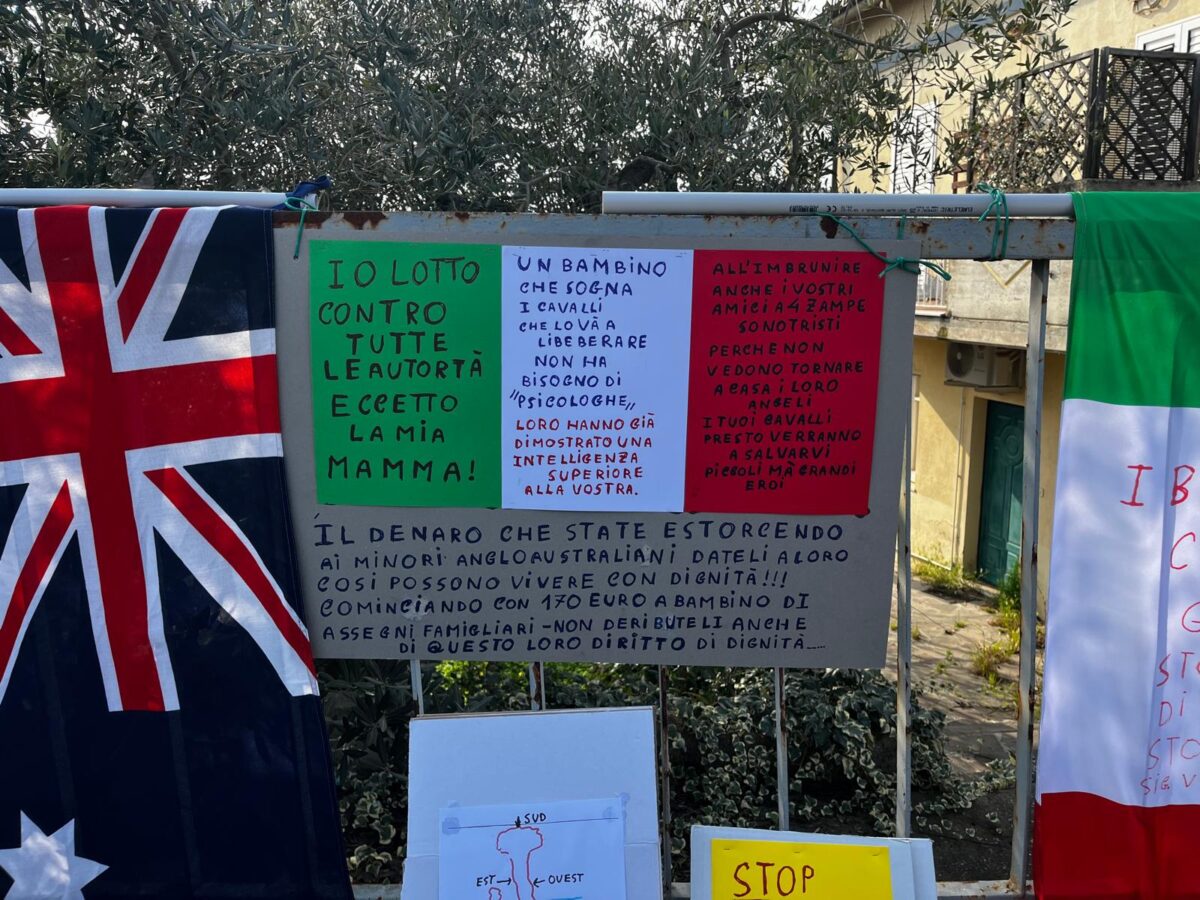 Family in the woods, sit-in outside foster home: signs and toys for the children